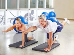 Mann und Frau machen gemeinsam Gymnastik im Fitnesscenter