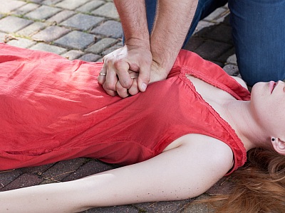 Ein Mann führt an einer Frau, die auf dem Boden liegt, eine Herzmassage durch.