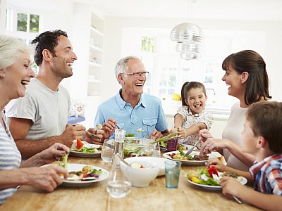 Mehrgenerationenfamilie sitzt beim gemeinsamen Essen am Tisch.