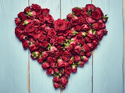 Herz aus roten Rosen auf Holzgrund.