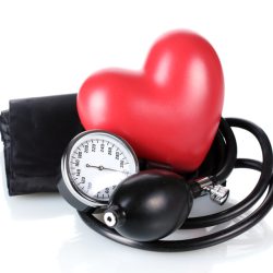 Ein rotes Herz mit Blutdruckmessgerät vor weißem Hintergrund