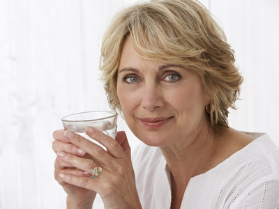 Eine Frau mit Osteoporose trinkt Heilwasser