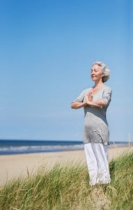 ältere Frau meditiert am Strand
