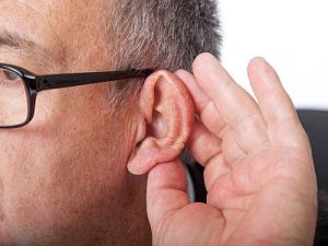 Ein Mann hält eine Hand hinters Ohr um besser zu hören.