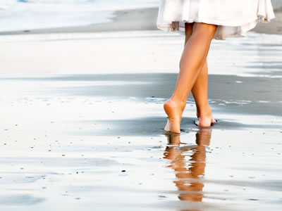Die Beine einer Frau beim Strandspaziergang