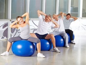 Glückliche Gruppe Senioren bei Rückentraining im Fitnesscenter auf Gymnastikbällen