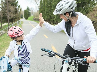 Mutter und Tochter fahren gemeinsam Rad und klatschen sich ab.