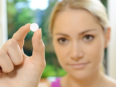 Frau betrachtet eine Tablette in ihrer Hand.