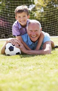 Opa und Enkel spielen fröhlich mit dem Fußball.
