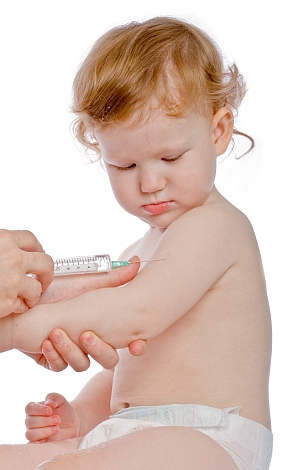 Ein kleines Kind schaut interessiert auf die Impfnadel.