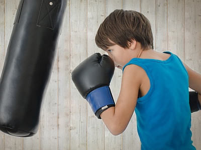 Junge im Sportdress boxt auf Boxsack.