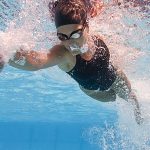 Unterwasseraufnahme einer Frau die im Schwimmbad krault.