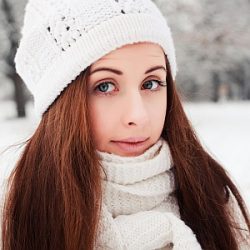 Junge Frau mit schönen Haaren und Mütze im Winter.