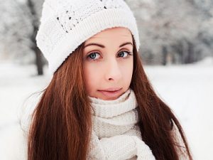 Junge Frau mit schönen Haaren und Mütze im Winter.