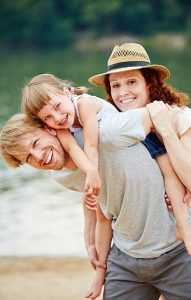 Glückliche Familie mit Tochter macht Urlaub im Sommer am See