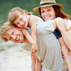 Glückliche Familie mit Tochter macht Urlaub im Sommer am See