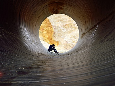 Mann sitzt depressiv im Tunnel.