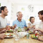 Mehrgenerationenfamilie sitzt beim gemeinsamen Essen am Tisch.