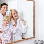 Vater, Mutte rund Kind putzen sich im Badezimmer die Zähne
