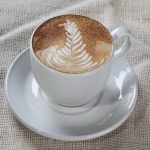 Eine Tasse Kaffee in weißer Tasse auf hellem Leinenuntergrund