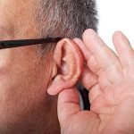 Ein Mann hält eine Hand hinters Ohr um besser zu hören.