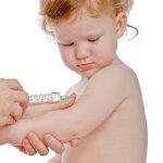Ein kleines Kind schaut interessiert auf die Impfnadel.