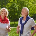 Zwei lächelnde Senioren joggen gemeinsam in der Natur im Sommer