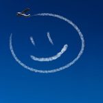 Flugzeug malt einen glücklichen Smiley an den blauen Himmel