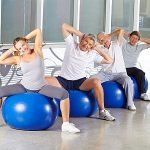 Glückliche Gruppe Senioren bei Rückentraining im Fitnesscenter auf Gymnastikbällen