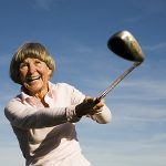 Ältere , fröhliche Frau mit Golfschläger